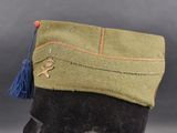 a green hat with a blue tassel on top of it