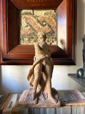 a statue of a woman sitting on top of a pile of books