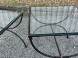 pair of glass and metal side tables on a gravel ground