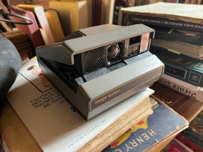 a polaroid camera sitting on top of a stack of books