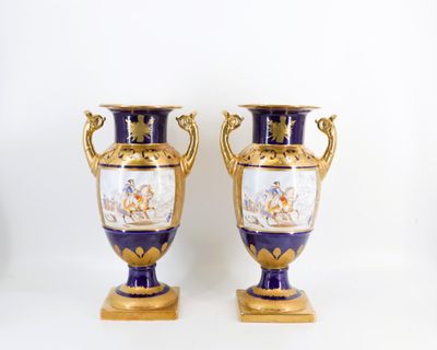 une paire de vases bleus et dorés posés sur une table blanche
