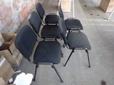 several black chairs are lined up against a brick wall