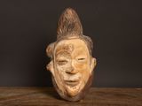 sculpture en bois représentant le visage d'un homme, posée sur une table en bois