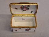 a small white box with a gold trim and flowers on it