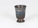 a silver cup sitting on a stand on a white surface