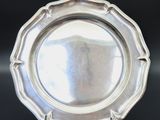 an antique silver plate on a black table with a black background