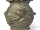 a silver vase with a statue on it on a white surface
