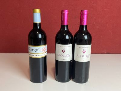 trois bouteilles de vin rouge posées sur une table près d'un mur rouge