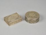 two small silver boxes sitting next to each other on a white surface