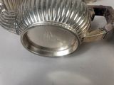 a silver teapot with a handle on a white table