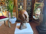 statue of a man ' s head on a pedestal in front of a cabinet