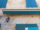 blue shutters on the side of a building with a street sign on it