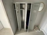 two metal lockers in a room with a mirror on the wall