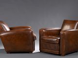 pair of brown leather club chairs on a grey background