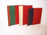 four different colored books lined up on a white surface