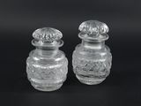 pair of clear glass salt and pepper shakers on a black background