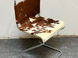 a chair with a cow print seat and a metal frame
