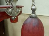 a red glass lamp hanging from a silver metal light fixture
