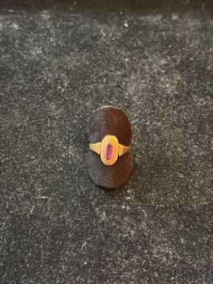 a close up of a ring with a red stone on a black surface