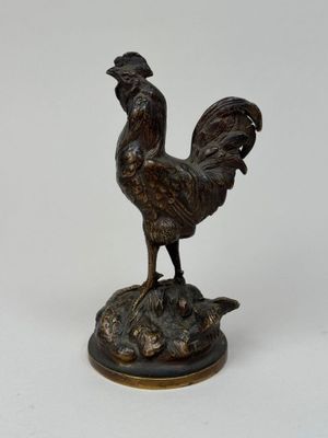 statue en bronze représentant un coq posé sur un rocher, sur fond blanc