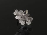 bague en forme de fleur plaquée argent sur fond noir avec reflets