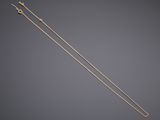 a pair of gold plated knitting needles on a grey background