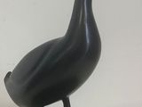 statue of a black duck on a marble base on a white background