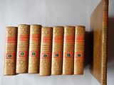 Six vieux livres sont alignés sur une étagère à côté d'une bibliothèque.