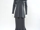 Le mannequin porte une robe noire ornée de volants.