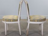 pair of white painted chairs with upholstered back cushions