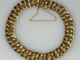 gros plan d'un collier en or sur une surface blanche