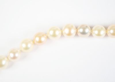 a close up of a pearl necklace on a white surface