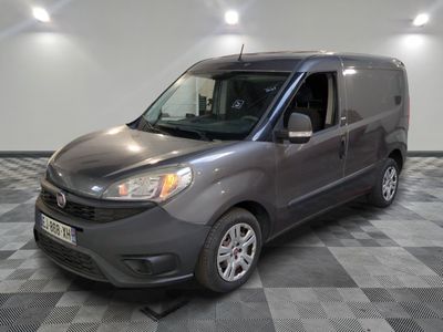 La camionnette grise est garée sur un sol carrelé à damier.