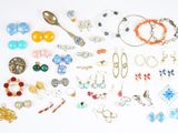 many pairs of earrings and bracelets laid out on a white surface