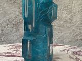 un vase en verre bleu posé sur une table recouverte d'une nappe rouge et blanche