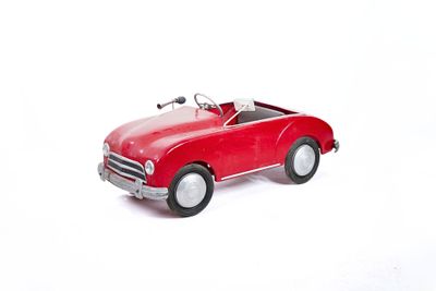 a red toy car that is sitting on a white surface