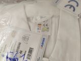 a white shirt with a tag on it sitting in a plastic bag