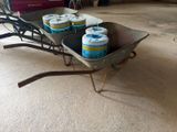 Plusieurs canettes de bière se trouvent dans une brouette, dans un garage.
