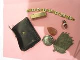 un sac à main noir et quelques autres objets posés sur une surface rose