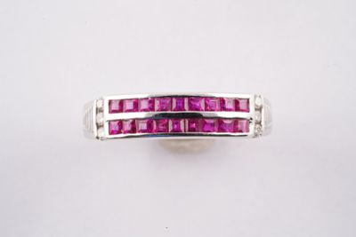 un gros plan d'une bague ornée de pierres roses sur un fond blanc