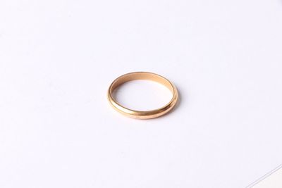 a close up of a gold ring sitting on top of a white surface