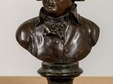 bronze bust of a man on a pedestal on a wooden table