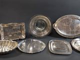 a lot of silver dishes and trays sitting on a table