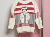 un pull blanc avec un pull rayé rouge et gris, suspendu à un cintre
