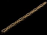 a close up of a gold chain bracelet on a black background