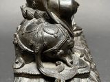 silver statue of a person with a snake on top of it