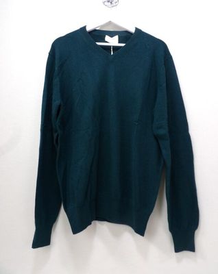 a green sweater hanging on a white wall next to a hanger