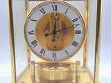 une horloge en or avec des chiffres romains, exposée dans une vitrine