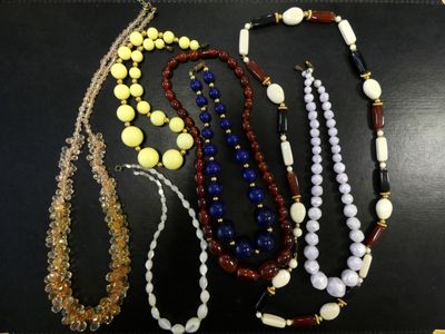 several necklaces of various colors and sizes on a black surface