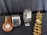 three different watches and bracelets sitting on a table
